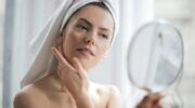 Vrouw bekijkt haar huid in een handspiegel.