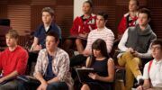 De cast van Glee in een lokaal.