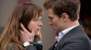 Man en vrouw kijken heel intens naar elkaar. De man houdt de vrouw haar gezicht vast. Scene uit 50 shades of grey/