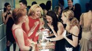 De meiden uit Sex And The City lachen met een drankje in hun handen.