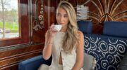 Foto van influencer Gina Singels. Ze zit in een trein koffie te drinken.