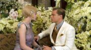 Gatsby en Daisy kijken elkaar aan en om hun heen zitten veel bloemen.
