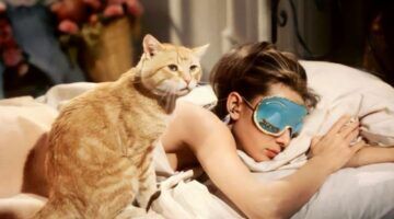 Audrey Hepburn in Breakfast at Tiffany's. Ze ligt op bed met een kat naast haar.