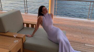 Kendall Jenner in een paarse jurk ligt op een bank.