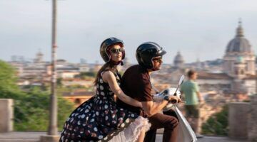 Scène uit Emily in Paris waar Emily achterop de scooter bij Marcello zit.