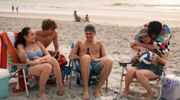 Scène uit The Summer I Turned Pretty waar Belly, Jeremiah, Conrad, Steven en Taylor op het strand zitten.