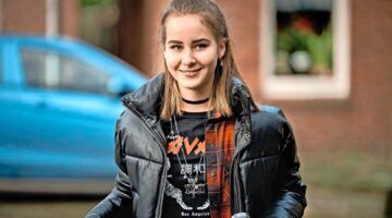 Meisje zit op een fiets, ze kijkt lachend voor zich uit. Scène uit de serie Oogappels.