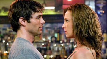 De twee hoofdkarakters van 27 Dresses kijken elkaar intens aan.