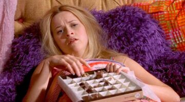 Meisje ligt op bed en eet hele bak chocolaatjes.