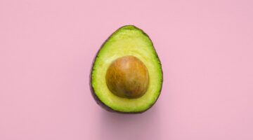 Een avocado met een roze achtergrond.