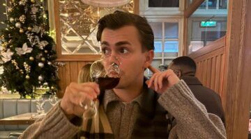 Foto van zanger Flemming. Hij kijkt opzij, terwijl hij een slok neemt van zijn glas rode wijn.