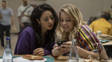 Twee meiden kijken lachend naar een telefoon.