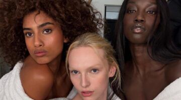 Drie modellen poseren met make-up op in een witte badjas.