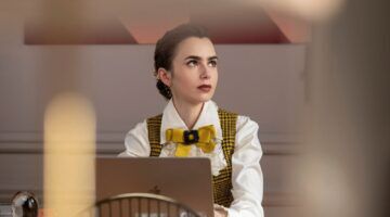 Emily uit Emily in Paris achter haar bureau.