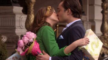 Leighton Meester en Ed Westwick als Blair en Chuck in de serie Gossip Girl. Ze geven elkaar een kus, terwijl ze een cadeau en een bos bloemen vasthouden.