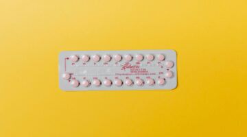 Anticonceptie pil met gele achtergrond.