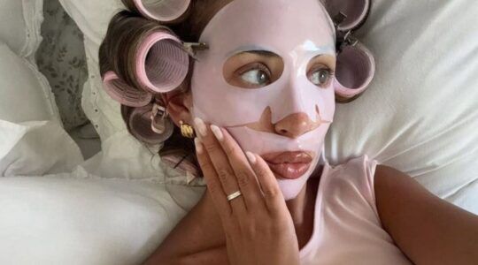 Meisje ligt met gezichtsmaskertje op in bed.