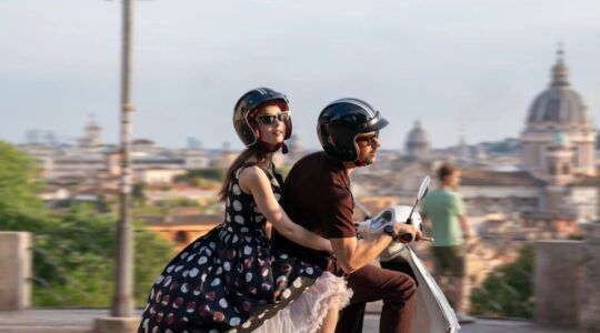 Scène uit Emily in Paris waar Emily achterop de scooter bij Marcello zit.