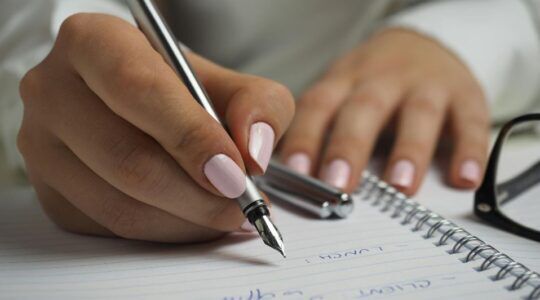 Vrouw schrijft op papier met pen.