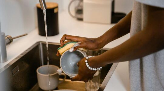 Een vrouw is de vaat aan het afwassen.