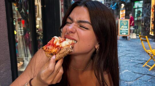 Meisje eet pizza op een terras.