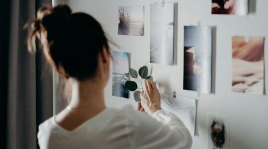 Een vrouw hangt foto's op in haar kamer.