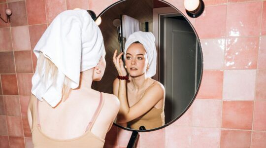 Een vrouw doet haar make-up in de badkamer.