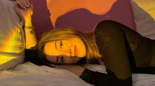 Foto van meisje dat op bed ligt. De zon straalt op haar gezicht.