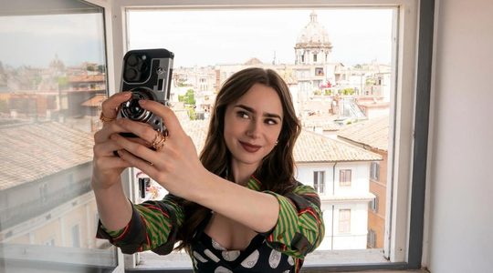 Lily Collins in de serie Emily in Paris. Ze neemt een selfie.