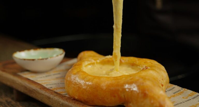 Iemand die een stukje van een kaas-knoflookbrood pakt.