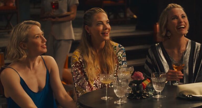 Sc&egrave;ne uit The White Lotus waar drie vrouwen op een rijtje zitten en lachen.