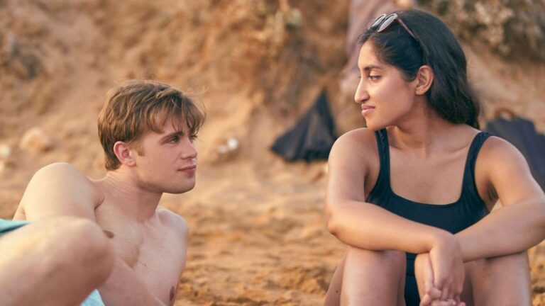 twee mensen uit one day op het strand kijken elkaar aan