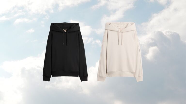 De Gap x BE&Iacute;S travel hoodie in zwart en beige, op een wolken achtergrond.