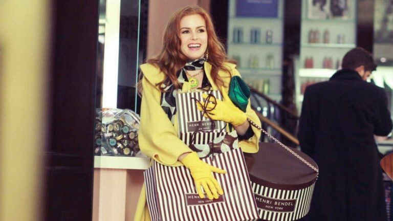 Het hoofdkarakter uit Confessions Of A Shopaholic heeft meerdere tasjes vast.