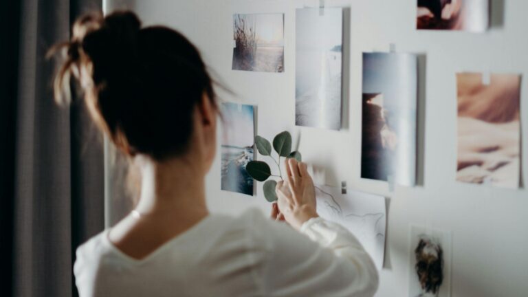 Een vrouw hangt foto's op in haar kamer.