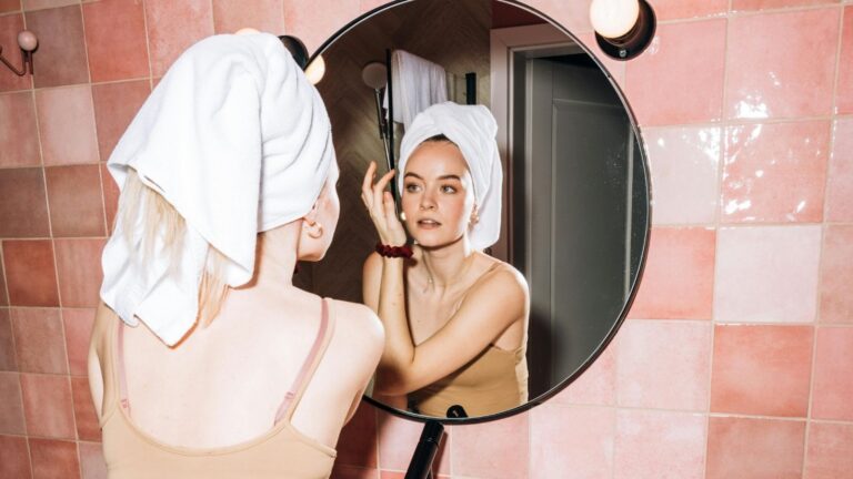 Een vrouw doet haar make-up in de badkamer.