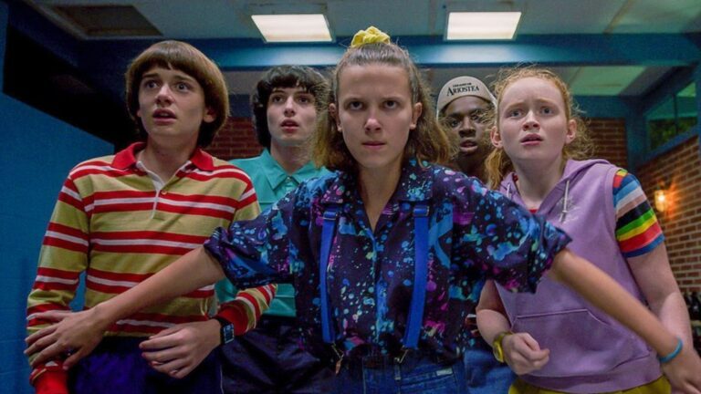 Foto van de castleden van Stranger Things. Ze kijken geschokt voor zich uit.