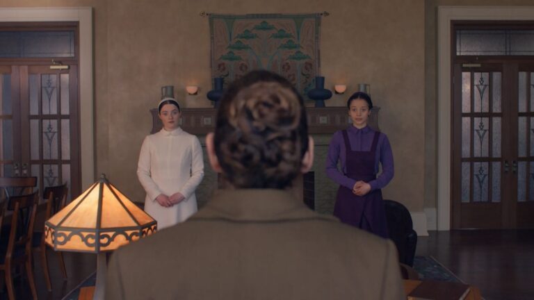Twee vrouwen kijken een andere vrouw aan in een donkere kamer.