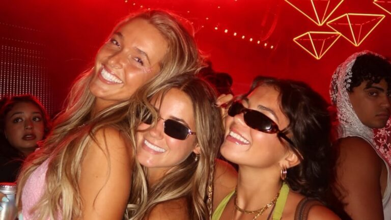 Drie meiden middenin het publiek van een festival. Ze lachen hard.