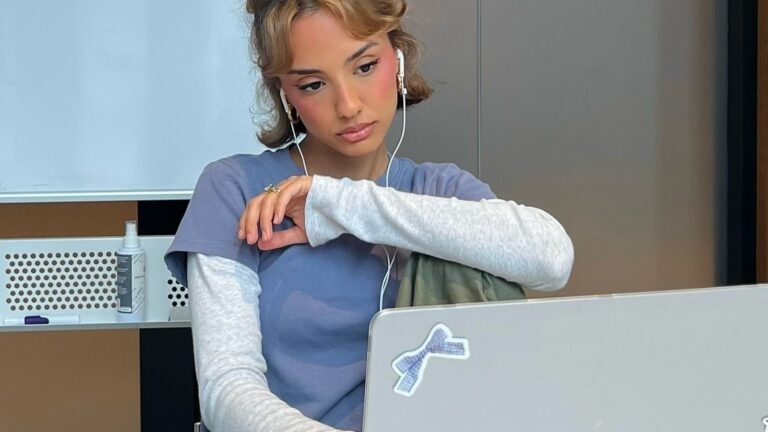 Meisje zit achter een laptop. Ze kijkt verdrietig voor zich uit.