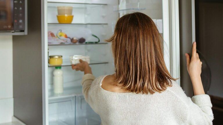Vrouw haalt kliekjes uit de koelkast.