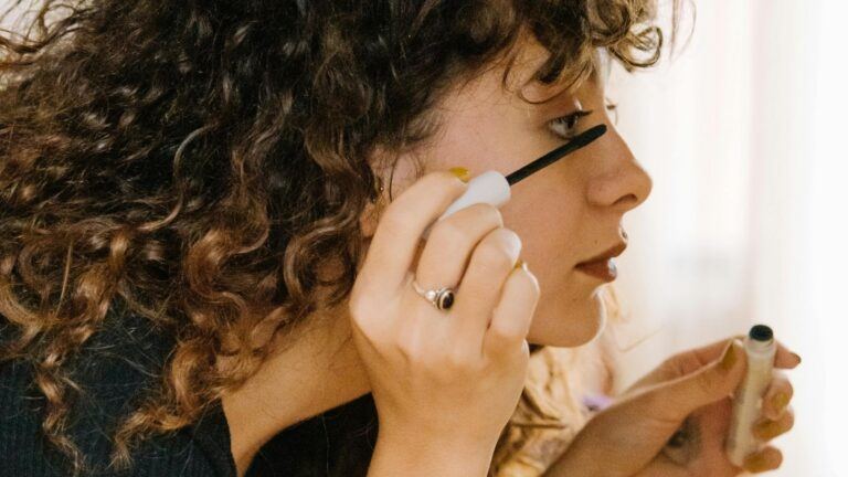 Een vrouw doet mascara op haar wimpers.