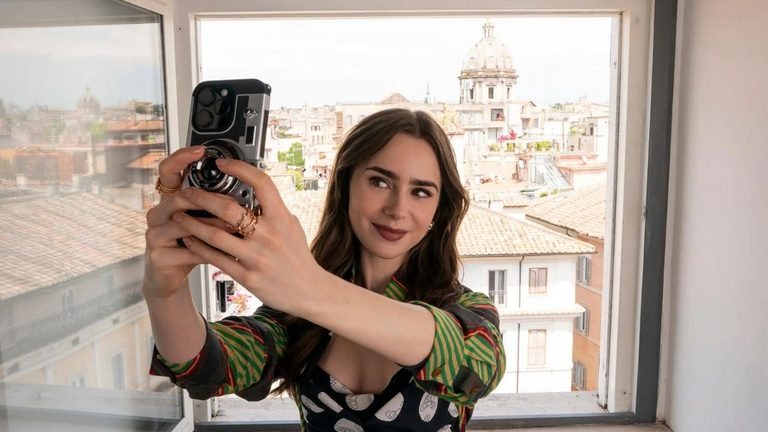 Lily Collins in de serie Emily in Paris. Ze neemt een selfie.