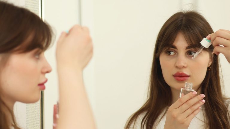 Vrouw doet haar skincare in de spiegel.