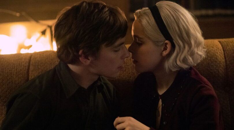 Harvey en Sabrina zoenen bijna voor de open haard in Chilling Adventures of Sabrina.