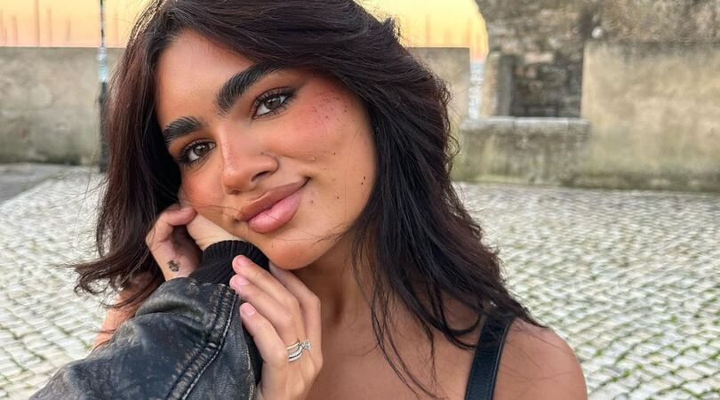 Een jonge vrouw kijkt liefdevol de camera in.