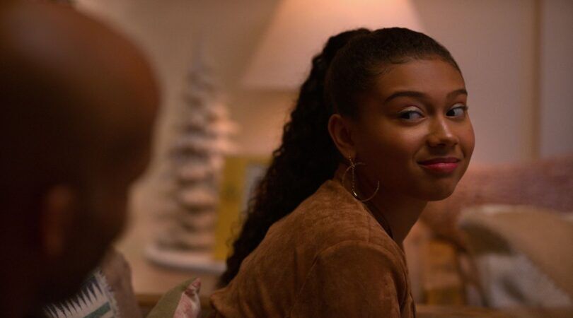 Een meisje kijkt lachend naar de camera.