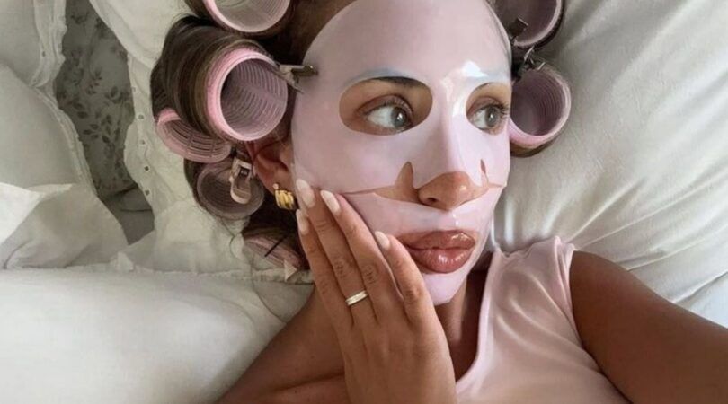 Meisje ligt met gezichtsmaskertje op in bed.