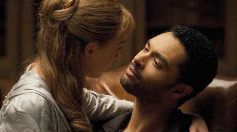 Een vrouw zit op schoot bij een man en ze kijken elkaar aan.