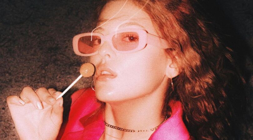 Meisje met een roze zonnebril en een lollipop in haar handen.